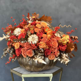 Orange and red rose arrangement in a metallic pumpkin container