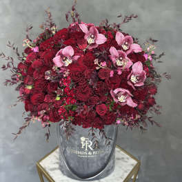 Large bouquet of red roses and pink orchids in a gray hatbox
