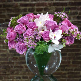 Pink rose bouquet with white orchids in a clear glass vase