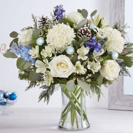 White and blue floral arrangement in a clear glass vase