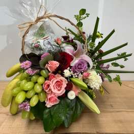 Fruit basket with roses, lilies, and grapes in a wicker handle wrap