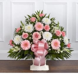 Pink and white floral arrangement with a pink ribbon bow in a white container