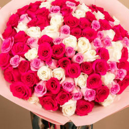 Large bouquet of pink, red, and white roses wrapped in pale pink paper