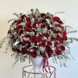 Large bouquet of red roses with baby's breath in a white vase
