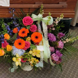 Colorful mixed flower arrangement with roses, gerberas, and orchids in a basket