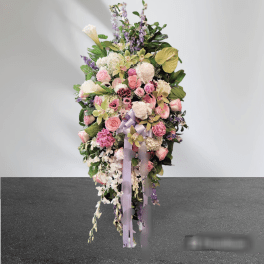 Tall pastel floral standing spray with pink and white blooms and lavender ribbon