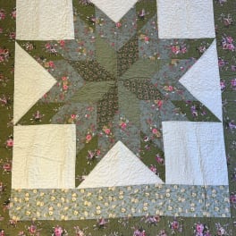 Patchwork quilt with a large green and cream star and floral patterned fabrics