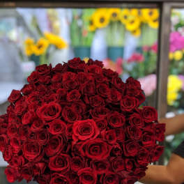 Large bouquet of red roses held in front of a flower shop