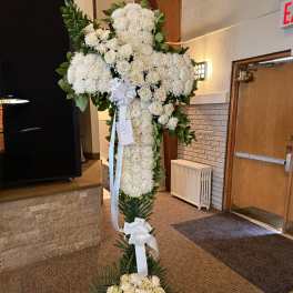 Tall white floral standing cross with ribbon bows