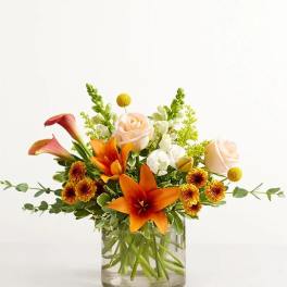 Orange lilies and pale roses in a glass vase