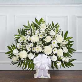 White floral spray with daisies and roses in a white stand