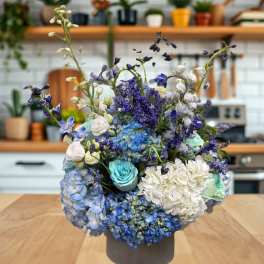 Blue and white floral arrangement in a gray vase