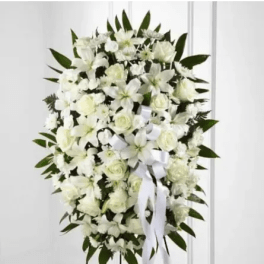 White funeral spray with lilies and roses on a standing easel