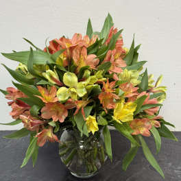 Bouquet of orange, yellow, and pink flowers in a glass vase