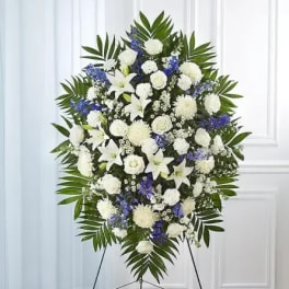 Standing funeral spray of white and blue flowers on an easel