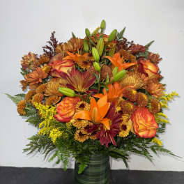 Autumn bouquet of orange and burgundy flowers in a green glass vase