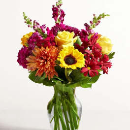 Mixed bouquet of bright flowers in a clear glass vase