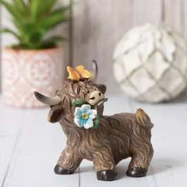 Small decorative cow figurine with flowers on its head and neck