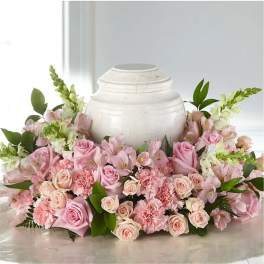 Pink roses and carnations arranged around a white urn