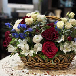 Basket arrangement of red and white roses with blue flowers