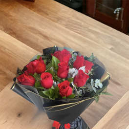 Bouquet of red roses wrapped in black paper with gold trim