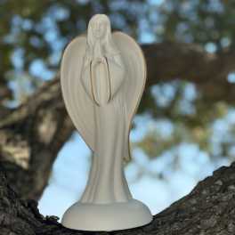 White angel figurine standing on a tree branch