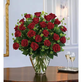 Red roses arranged in a clear glass vase on a table