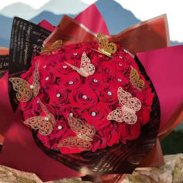 Bouquet of red roses wrapped in dark paper with butterfly decorations