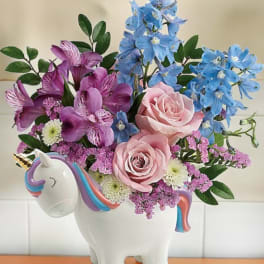 Pink and blue flowers arranged in a unicorn-shaped vase
