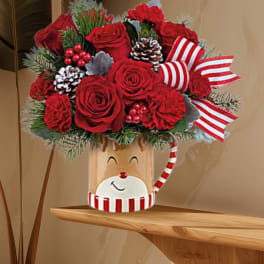 Red roses in a festive holiday container with striped ribbon and pinecones
