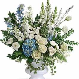 White and blue floral arrangement in a white pedestal vase