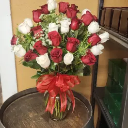 Bouquet of red and white roses in a glass vase with a red ribbon
