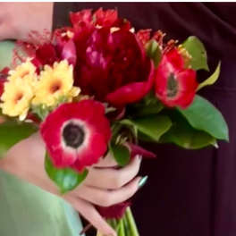 Handheld bouquet of red anemones and yellow daisies