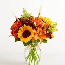 Sunflower and orange lily bouquet in a clear glass vase