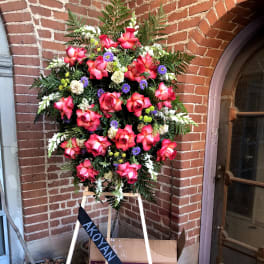 Standing spray of hot pink roses with purple and green accents on a wooden easel