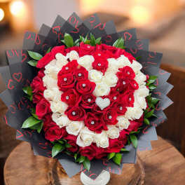 Red and white rose bouquet in black wrap with a white vase