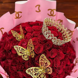 Bouquet of red roses wrapped in pink paper with gold butterfly accents