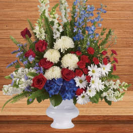 Red roses, white daisies, and blue flowers in a white vase
