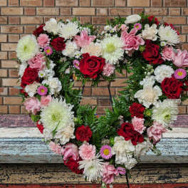 Heart-shaped floral wreath with red, pink, and white blooms