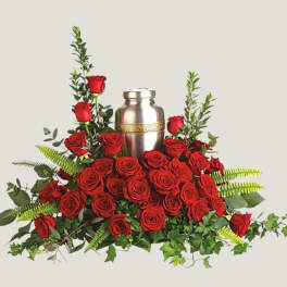 Red roses arranged around a silver urn with greenery