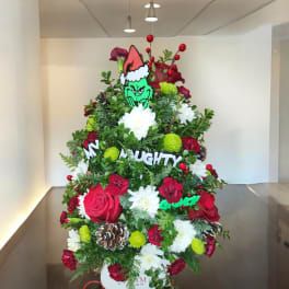Christmas tree-shaped floral arrangement with roses, mums, and a Grinch topper