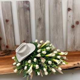 White floral arrangement with a white cowboy hat on top