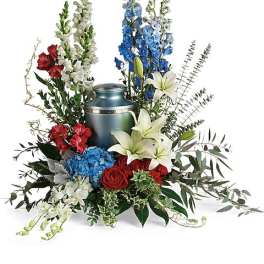 Floral funeral arrangement around a blue urn with red, white, and blue flowers
