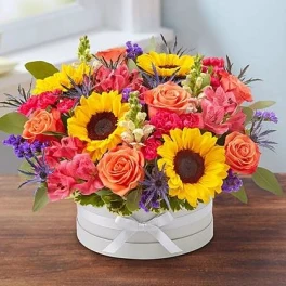 Bright mixed bouquet with sunflowers and roses in a white hat box
