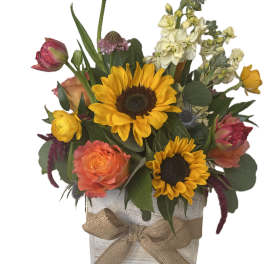 Mixed bouquet with sunflowers, roses, and tulips in a rustic wooden box