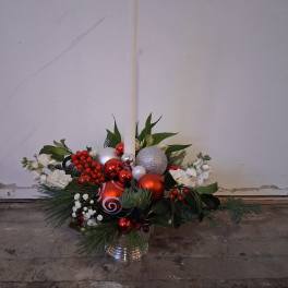 Holiday floral arrangement with red and silver ornaments in a metal container