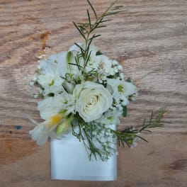 White floral corsage with a rose and small blooms on a white band