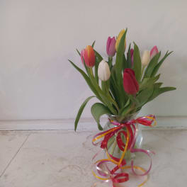 Tulips in a clear glass vase with a pink ribbon bow