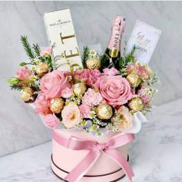 Pink rose bouquet with chocolates and champagne in a round gift box