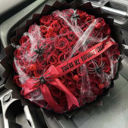 Red rose bouquet with spider decorations and a ribbon in a car seat
